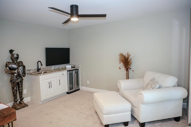 living area featuring beverage cooler, ceiling fan, light carpet, and baseboards