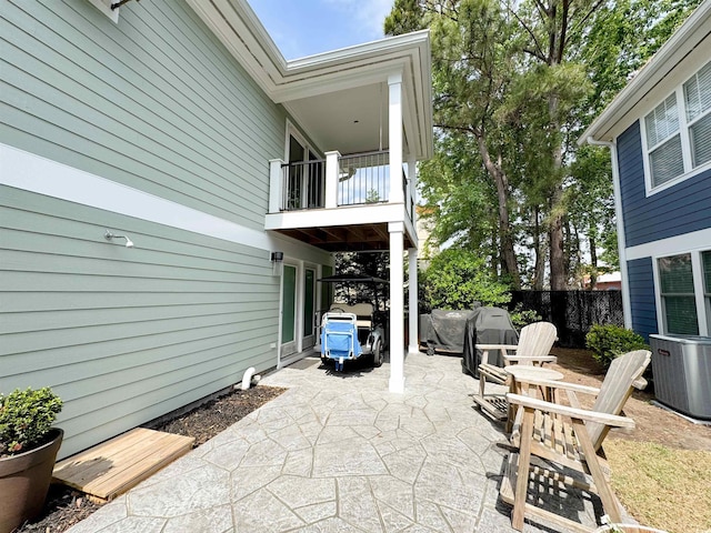 view of patio featuring a balcony, central AC unit, and fence