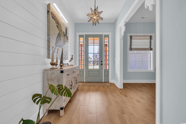 foyer featuring light wood finished floors, a chandelier, and baseboards