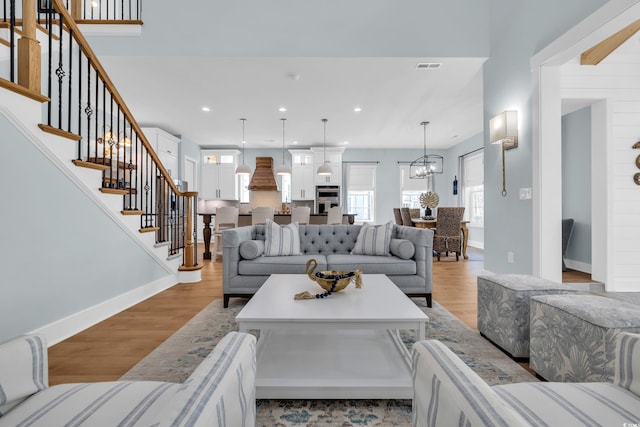 living room with baseboards, stairs, a chandelier, light wood-style flooring, and recessed lighting