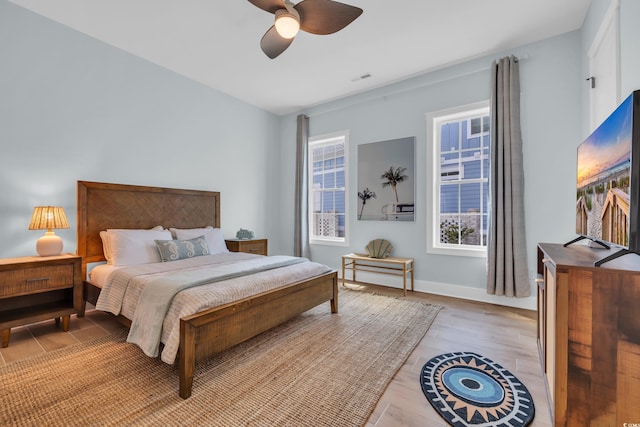 bedroom with ceiling fan, light wood-style floors, and baseboards
