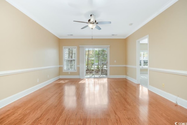 empty room featuring healthy amount of natural light, a ceiling fan, light wood finished floors, baseboards, and ornamental molding