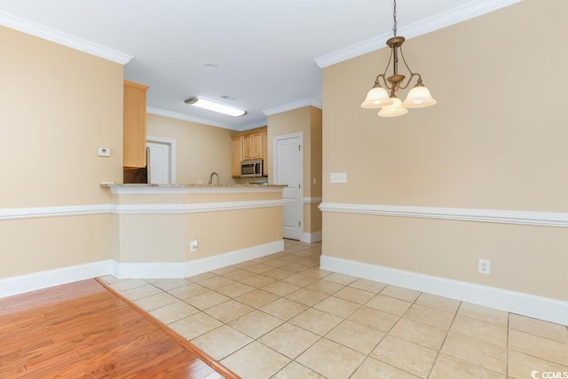 unfurnished room with ornamental molding, a chandelier, baseboards, light wood-style floors, and a sink