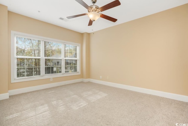 unfurnished room with light colored carpet, baseboards, and a ceiling fan