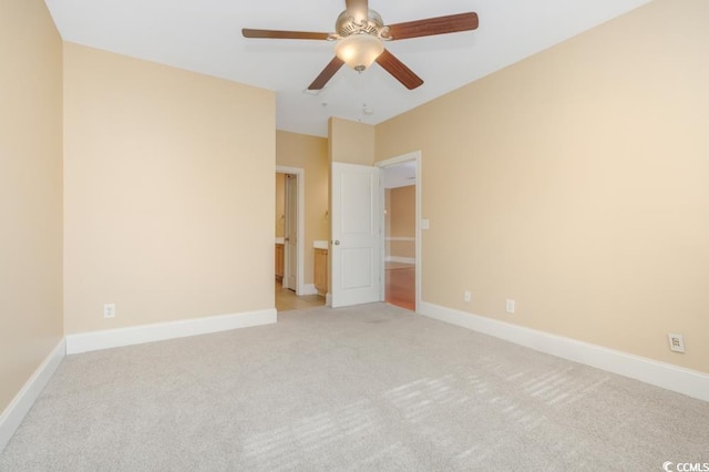 spare room with light colored carpet, ceiling fan, and baseboards