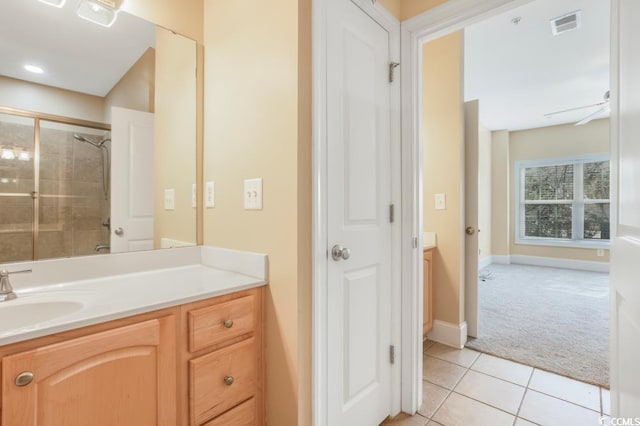 bathroom featuring vanity, tile patterned floors, baseboards, and a tile shower