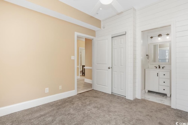 unfurnished bedroom featuring carpet floors, a sink, a closet, and baseboards
