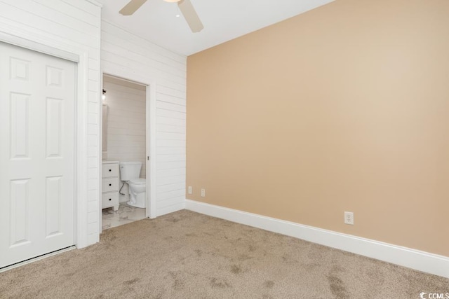 unfurnished bedroom with carpet, ensuite bathroom, baseboards, ceiling fan, and a closet