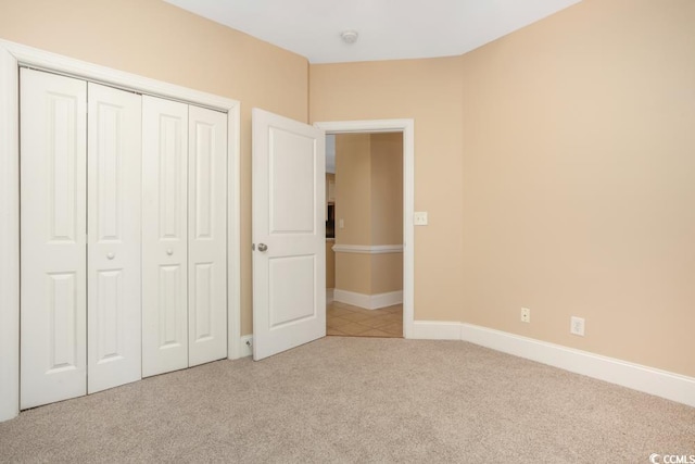 unfurnished bedroom featuring carpet floors, a closet, and baseboards