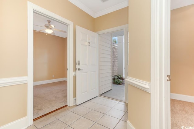 foyer featuring light colored carpet, a ceiling fan, ornamental molding, and light tile patterned floors