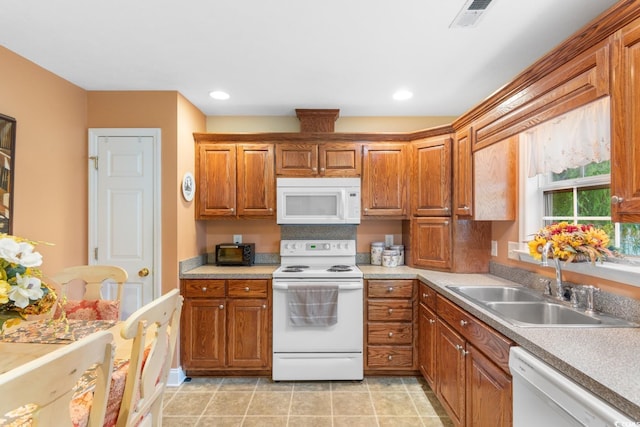 kitchen featuring a sink, white appliances, light countertops, brown cabinetry, and visible vents