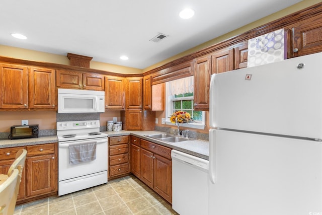 kitchen featuring a sink, brown cabinets, white appliances, and visible vents