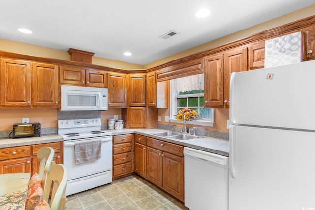kitchen with brown cabinets, a sink, white appliances, light countertops, and visible vents