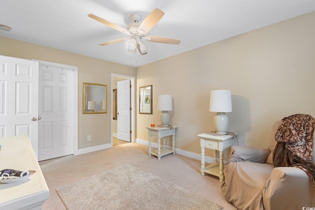 sitting room with baseboards, a ceiling fan, and light colored carpet