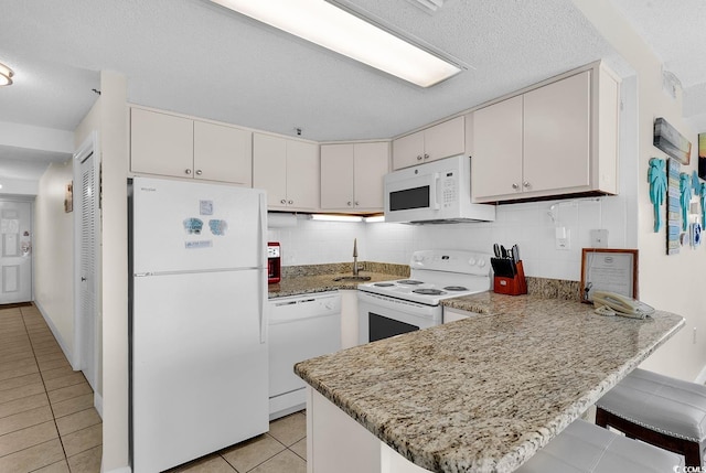 5511 N Ocean Blvd Unit 209, Myrtle Beach, SC 29577 - kitchen featuring white appliances, a peninsula, light tile patterned floors, decorative backsplash, and a textured ceiling