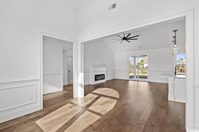 163 Sago Palm Dr, Myrtle Beach, SC 29579 - unfurnished living room featuring a glass covered fireplace, dark wood-style flooring, ceiling fan, a towering ceiling, and crown molding
