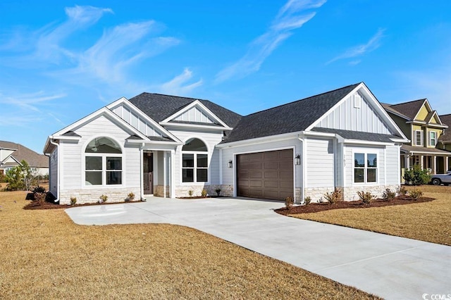 view of front of house featuring board and batten siding, stone siding, an attached garage, and a front lawn