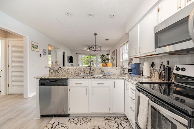 619 Waterway Village Blvd Unit 7C, Myrtle Beach, SC 29579 - kitchen featuring light stone countertops, a sink, stainless steel appliances, white cabinetry, and a peninsula