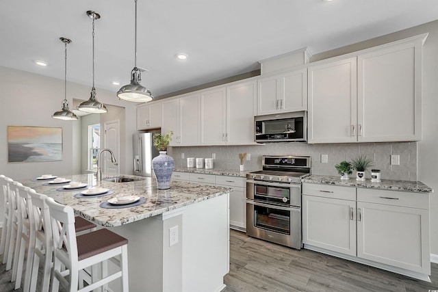 186 Glengrove Ln, Murrells Inlet, SC 29576 - kitchen with tasteful backsplash, a sink, light wood finished floors, stainless steel appliances, and white cabinetry