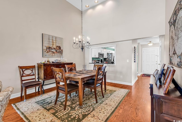 4755 Lightkeepers Way Unit 15-E, Little River, SC 29566 - dining room with baseboards, a high ceiling, light wood-style flooring, and a notable chandelier