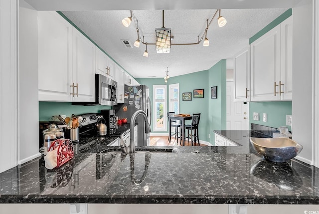 4755 Lightkeepers Way Unit 15-E, Little River, SC 29566 - kitchen featuring a textured ceiling, track lighting, a peninsula, stainless steel appliances, and white cabinetry