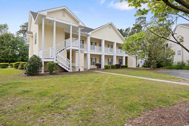 greek revival inspired property with a front lawn, stairway, and a porch