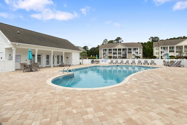 community pool with fence, a patio, and french doors