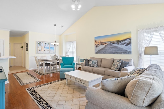 living room with light wood-style floors, a chandelier, and high vaulted ceiling