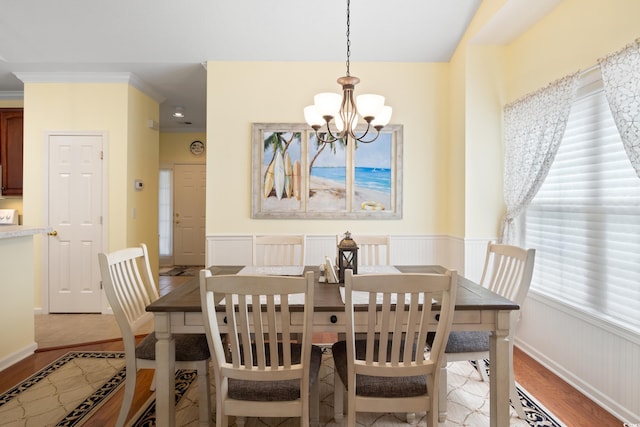 dining area with wood finished floors, a chandelier, and a wainscoted wall