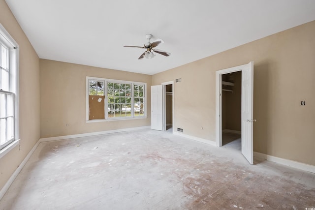 unfurnished bedroom with two closets, ceiling fan, and baseboards