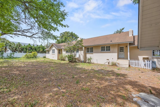 view of front of property with fence, entry steps, and stucco siding