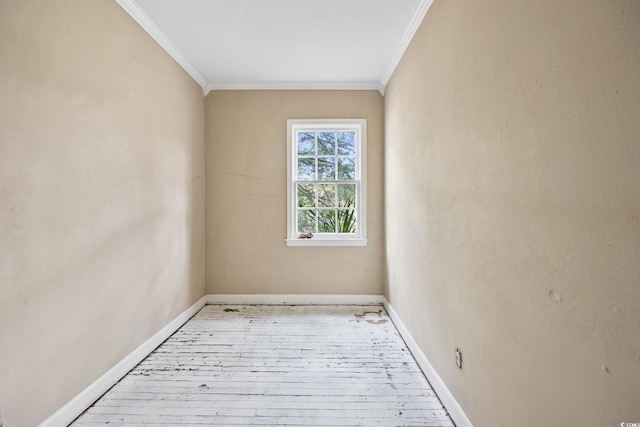 empty room with hardwood / wood-style flooring, baseboards, and ornamental molding