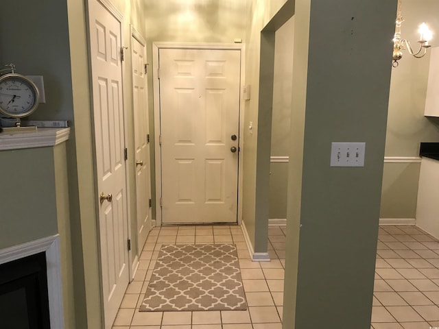 doorway to outside featuring light tile patterned floors, baseboards, and a chandelier