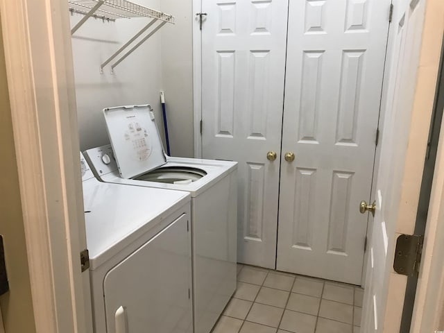 clothes washing area featuring laundry area, light tile patterned floors, and washer and dryer