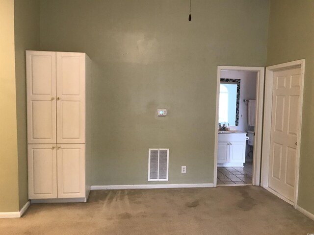 empty room with visible vents, a sink, baseboards, and light carpet