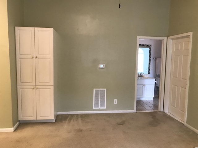 empty room featuring visible vents, a sink, baseboards, and light carpet