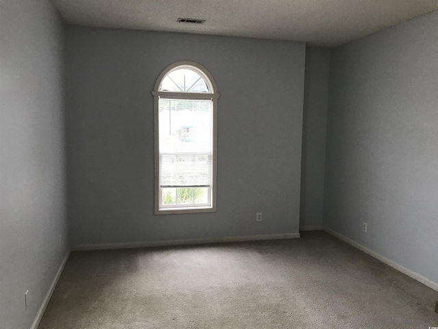 carpeted empty room with baseboards, visible vents, and plenty of natural light