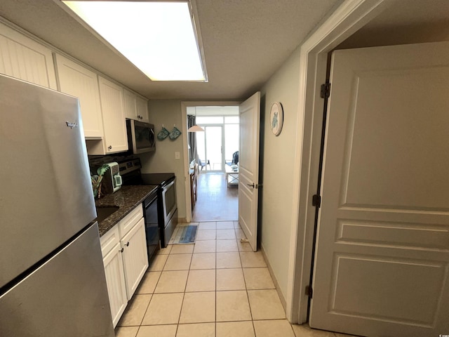2701 S Ocean Blvd Unit 1507, North Myrtle Beach, SC 29582 - kitchen with stainless steel appliances, white cabinets, light tile patterned floors, tasteful backsplash, and baseboards