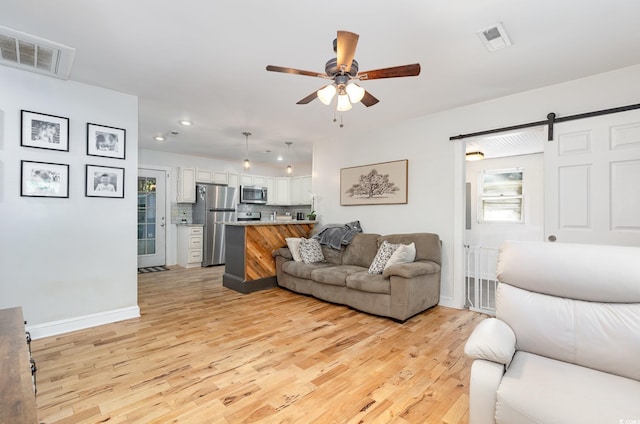 508 Pearl St, Conway, SC 29527 - living room featuring a barn door, light wood-style floors, visible vents, and a ceiling fan
