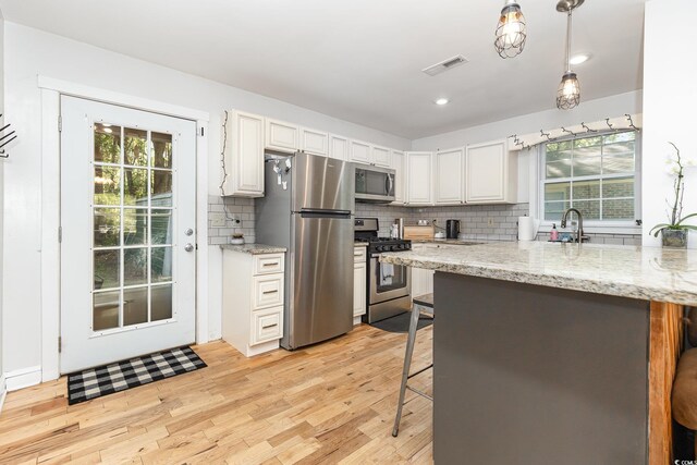 508 Pearl St, Conway, SC 29527 - kitchen with light wood finished floors, stainless steel appliances, visible vents, tasteful backsplash, and a breakfast bar area