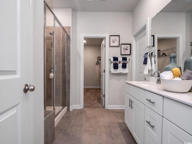bathroom featuring a shower stall, a walk in closet, and vanity