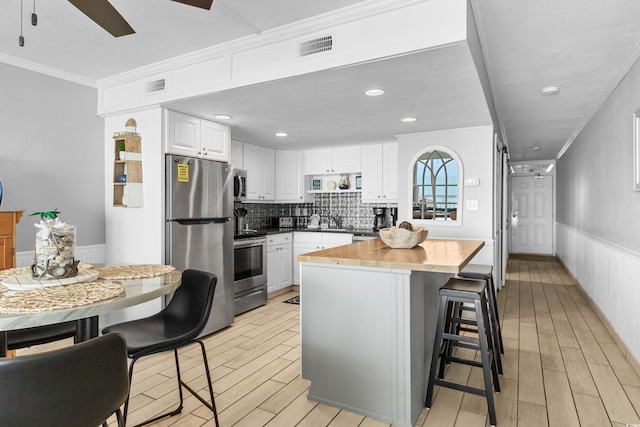 1012 N Waccamaw Dr Unit 507, Murrells Inlet, SC 29576 - kitchen featuring stainless steel appliances, ornamental molding, white cabinets, light wood finished floors, and tasteful backsplash