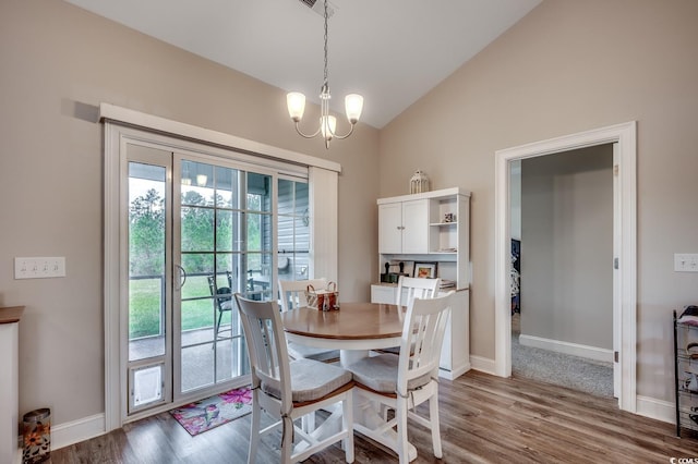 dining space with baseboards, vaulted ceiling, wood finished floors, and a notable chandelier