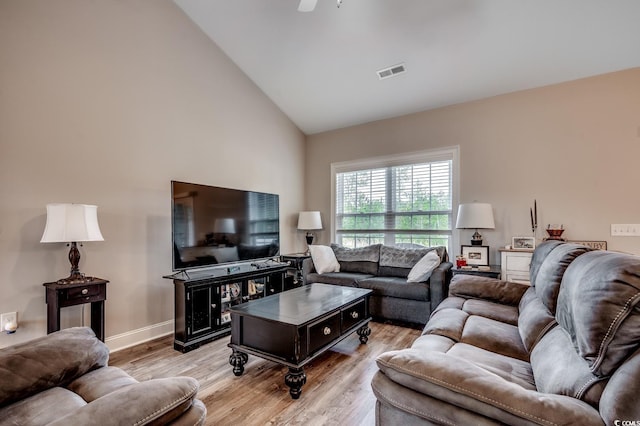 living room with light wood finished floors, visible vents, and high vaulted ceiling