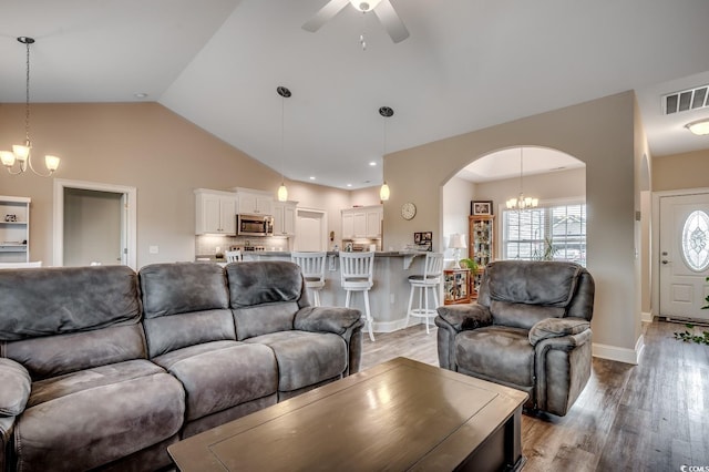 living room featuring ceiling fan with notable chandelier, arched walkways, light wood-style flooring, lofted ceiling, and visible vents