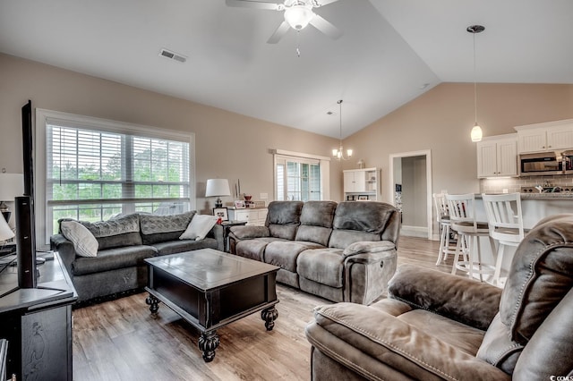 living room with light wood-style floors, visible vents, a ceiling fan, and high vaulted ceiling