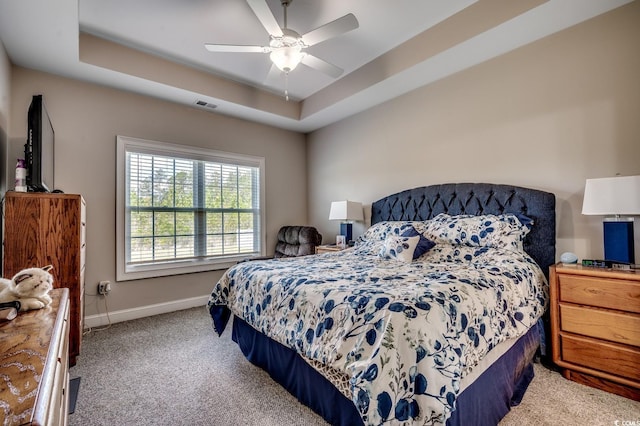 carpeted bedroom with baseboards, a ceiling fan, visible vents, and a raised ceiling