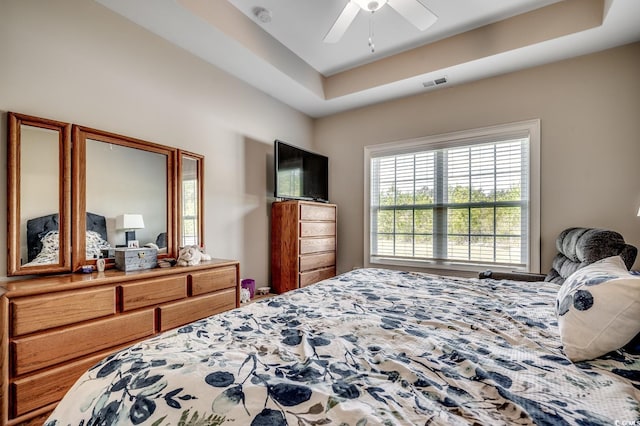 bedroom with ceiling fan, visible vents, and a raised ceiling