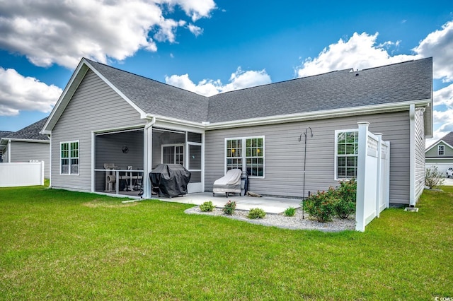 back of property with a lawn, a sunroom, and a patio area