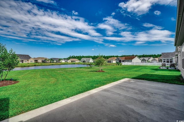 view of yard featuring a patio area, fence, a water view, and a residential view